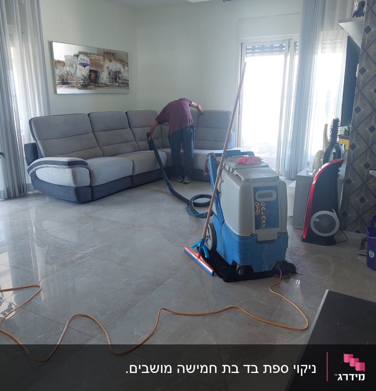 אדם מנקה ספה עם שואב אבק מקצועי